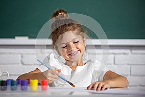 Painting school lesson, drawing art. Cute little girl child painting with paints color and brush. Drawing lesson in