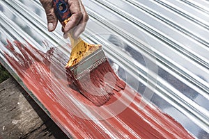 Painting the surface of a sheet of Galvanized Iron or GI corrugated metal with rust inhibiting red oxide primer