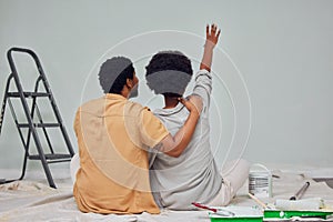 Painting, wall or black couple planning DIY, home renovation or house remodel together on floor. Back view, pointing or