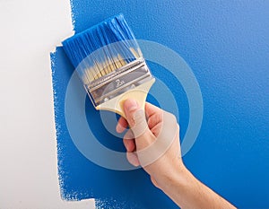 painting a wall blue with a paintbrush. photo