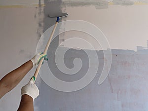 Painting the wall with a roller on a long handle