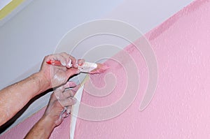 Painting wall of room. painting voids after masking tape. hands in the paint, close-up