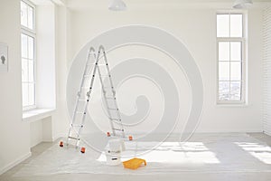 Painting in a white room with windows with a stepladder