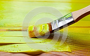 Painting the wooden surface of the board with a synthetic bristle brush with yellow paint