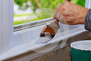 Painting a wooden with paintbrush while painting window trim photo