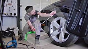 Paintless dent removal. A professional sits on a small stool and repairs a dent in a car without painting with a steel
