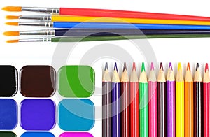 Paints, brushes and bright color pencils on a white background. School or education theme concept. Top view, flat lay, place for