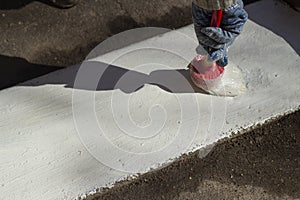 Paints the kerb with white paint. Brush with paint for the road curb