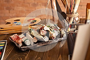 Paints and tools on wooden table in artist's workshop