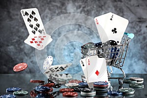 A pair of aces, hearts and diamonds, on a deck of playing cards. Poker playing chips in a blue shopping cart
