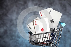 A pair of aces, hearts and diamonds, on a deck of playing cards. Poker playing chips in a blue shopping cart