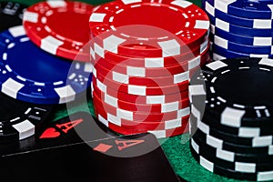 A pair of aces, hearts and diamonds, on a unique black deck of playing cards, surrounded by Blue, Red and Black betting chips on a