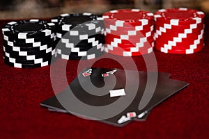 A pair of aces, hearts and Diamonds, with a unique Black faced deck of cards with Red and Black clay poker chips in a symmetrical