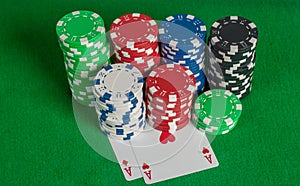 Pair aces and poker chips stack on green table