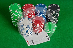 Pair aces and poker chips stack on green table