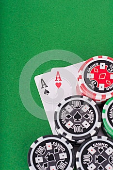 Pair of aces, red and black cassino chips on green table