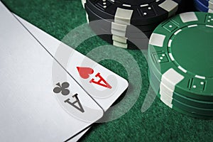 A pair of aces on the table with poker chips