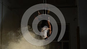 A pair of aerial acrobats trying to perform a trick in the smoke, men hanging upside down and trying to catch a woman