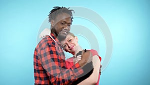 A pair of African male and a Caucasian woman together. holding a black cat and a white rat. blue background