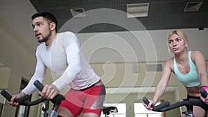 Pair of athletes accelerating on exercise bikes