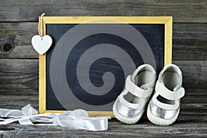 Pair of baby shoes and blank blackboard