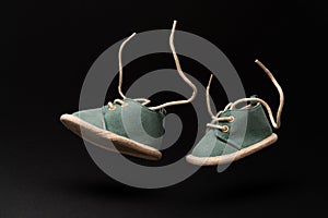 Pair of baby shoes flying in the air simulating walking on a black background