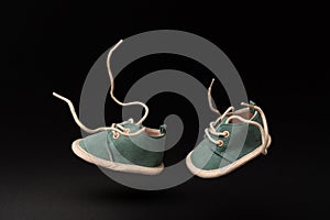 Pair of baby shoes flying in the air simulating walking on a black background