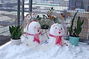 A pair of beautiful little snowmen are piled on the balcony