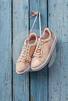 Pair of beige female sports shoes hanging