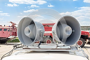 Pair of big retro loudspeakers on car roof. Fire trucks on background. Urgent or emergency announcement concept