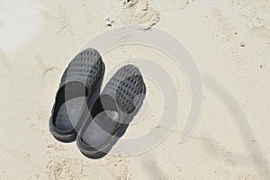 A Pair of Black Beach Shoes, Sandals or Flip Flops on White Sand Beach During A Hot Summer Day