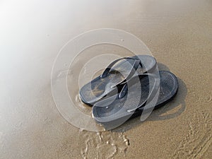 A Pair of Black Flip Flops on a Sandy Beach
