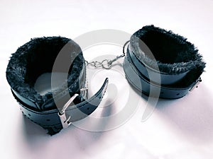 A pair of black furry leather sex toy handcuffs