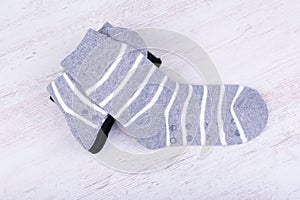 Pair of black and gray woolen socks on white wooden background