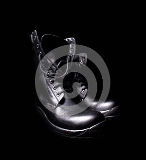 A pair of black leather military boots on black background