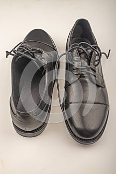 A pair of black leather shoes with laces on a white background. Close up