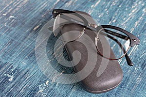 pair of black-rimmed optical glasses and a gray hard glasses case