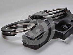 A pair of black and silver handcuffs laying on top of a black semi automatic pistol