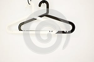 A pair of black and white plastic coat hangers with a trouser bar