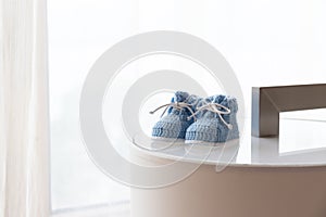 A pair of blue baby shoes against backlit window