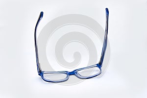 Pair of blue and black spectacles, on white background resting on lenses