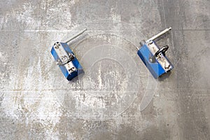 Pair of blue industrial lifting magnets on flat sheet metal surface.