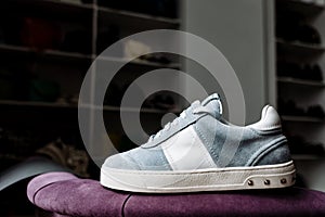 A pair of blue suede sneakers on a white sole with white accents on a background of shop