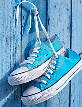 Pair of blue textile sneakers hanging on a nail