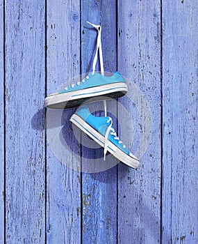 Pair of blue textile sneakers hanging on a nail