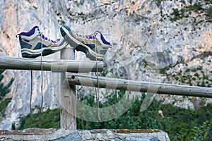 a pair of boots untied up and abandoned on a wooden railing and leaning on a post. The hiker has put out his boots to rest his
