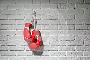 Pair of boxing gloves hanging on brick wall