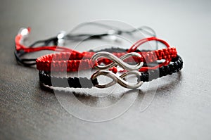 Pair bracelets in black and red with infinity. Handmade woven bracelets. Handmade decorations. Background with beads with hearts