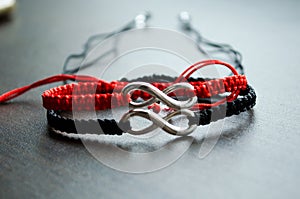 Pair bracelets in black and red with infinity. Handmade woven bracelets. Handmade decorations. Background with beads with hearts