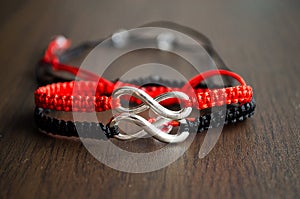 Pair bracelets in black and red with infinity. Handmade woven bracelets. Handmade decorations. Background with beads with hearts